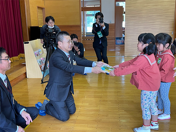 住田町立有住保育園様へ絵本13冊を寄贈。園児に絵本を手渡す様子