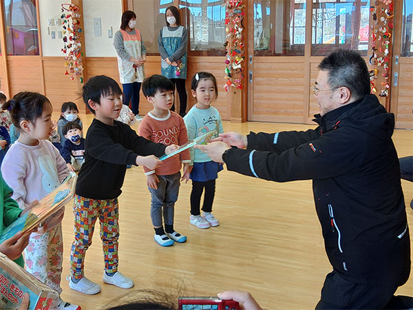 広田保育園への寄贈。園児へ絵本を手渡す様子