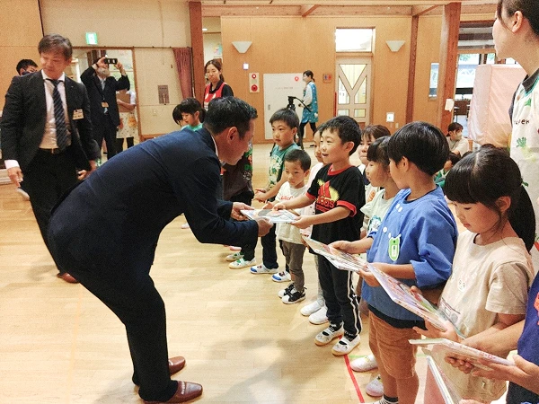 住田町立世田米保育園様へ絵本18冊を寄贈。園児に絵本を手渡す様子