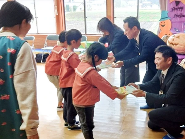 住田町立世田米保育園様へ絵本18冊を寄贈。園児に絵本を手渡す様子